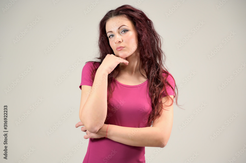 Portrait of a pretty slim brunette woman with emotions in a pink dress and with brown hair on a white background in the studio. The model is smiling and talking nicely. Portrait of a pretty slim brunette woman with emotions in a pink dress and with brown hair on a white background in the studio. The model is smiling and talking nicely.