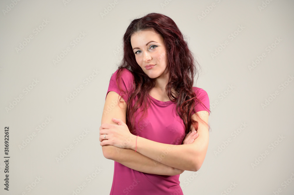 Portrait of a pretty slim brunette woman with emotions in a pink dress and with brown hair on a white background in the studio. The model is smiling and talking nicely. Portrait of a pretty slim brunette woman with emotions in a pink dress and with brown hair on a white background in the studio. The model is smiling and talking nicely.