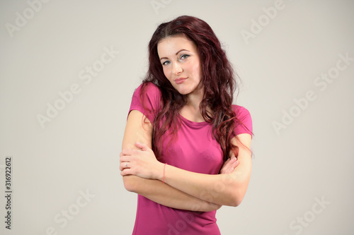 Portrait of a pretty slim brunette woman with emotions in a pink dress and with brown hair on a white background in the studio. The model is smiling and talking nicely.