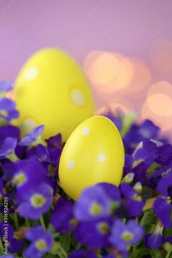 Easter holiday.Yellow easter eggs in bright violet colors on a light purple background with golden bokeh.Spring festive  background.