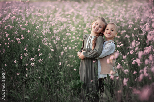 Portrait of two cute happy children. Twins boy and girl in summer. On a pink flowering field.