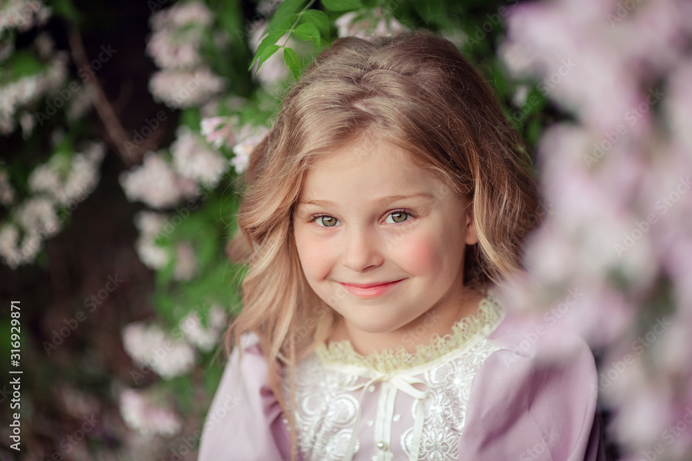 Portrait of a cute beautiful girl with blond hair in a pink dress in spring. On a walk in a flowered garden. Portrait of a cute beautiful girl with blond hair in a pink dress in spring. On a walk in a flowered garden.