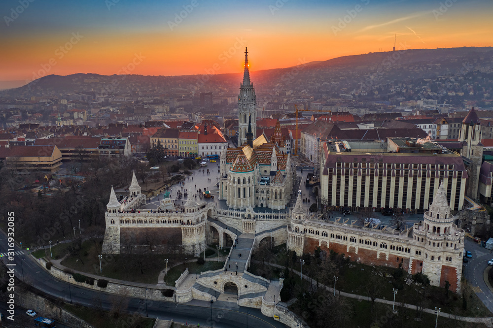 Budapest, Hungary - Aerial view of the famous Fisherman's Bastion (Halaszbastya) and Matthias Chruch at sunset with the sun right behind the church tower. Gold and blue sky at winter time