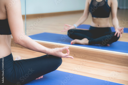 Beautiful Asian woman doing yoga meditation exercise in the room at sport club. 