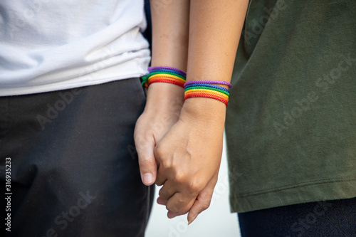 Photography hand of LGBT women holding together with rainbow ribbon symbol; concept of LGBT