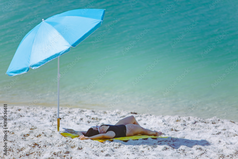 woman in swimsuit walking by sand beach blue sun umbrella and yellow blanket woman in swimsuit walking by sand beach blue sun umbrella and yellow blanket