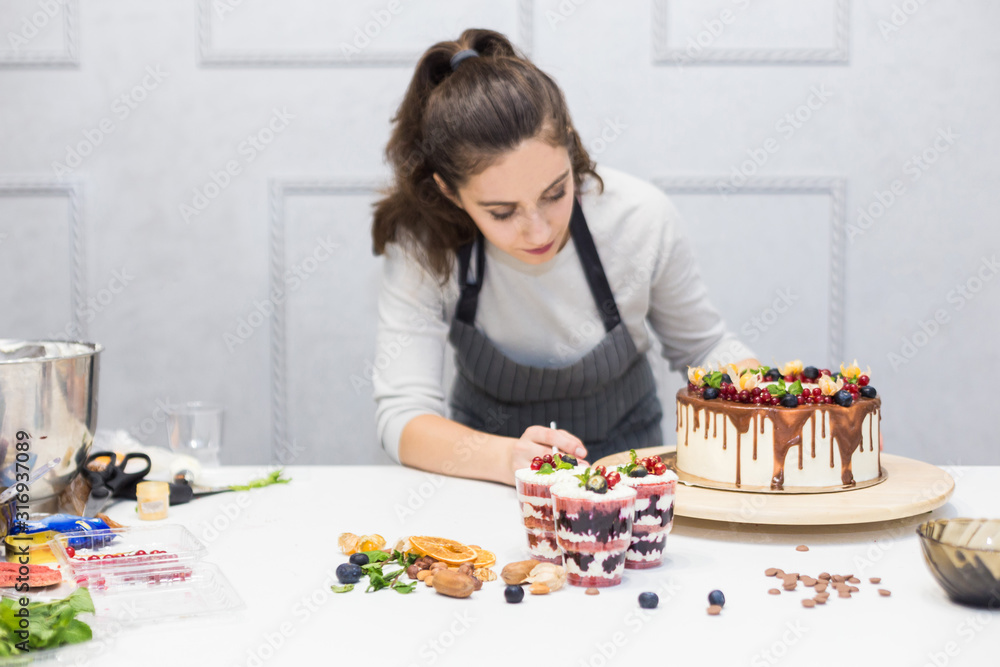 Decoration of the finished dessert. Pastry chef sprinkles confectionery with yellow powder. The concept of homemade pastry, cooking cakes. Decoration of the finished dessert. Pastry chef sprinkles confectionery with yellow powder. The concept of homemade pastry, cooking cakes.