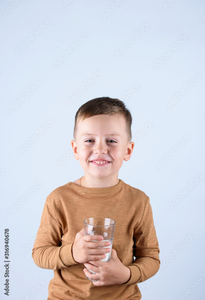 A beautiful little boy, in a brown sweater, holding a glass of milk. A beautiful little boy, in a brown sweater, holding a glass of milk.