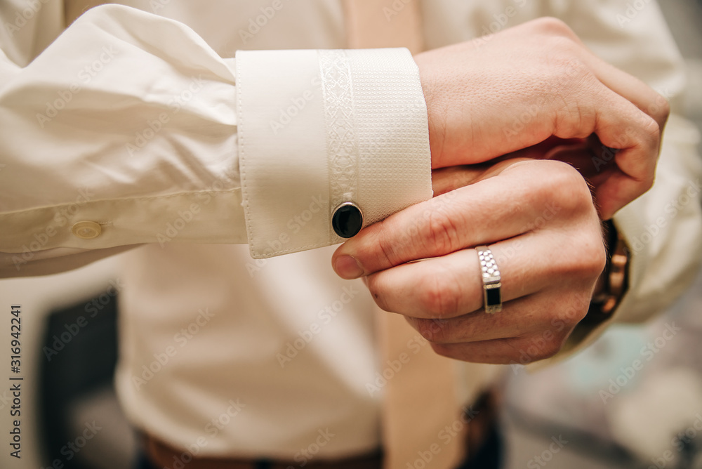 Man fastens cufflinks on his sleeve.