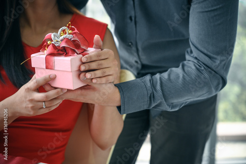View of male and female hand holding a gift box.