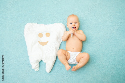 Fotografia Cute baby lies with a toothbrush on a blue background