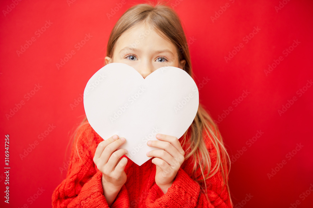 Lovely little girl holding large paper heart, over red background Lovely little girl holding large paper heart, over red background