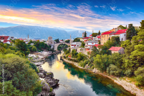 Fantastic Skyline of Mostar with the Mostar Bridge, houses and minarets, at sunset photo