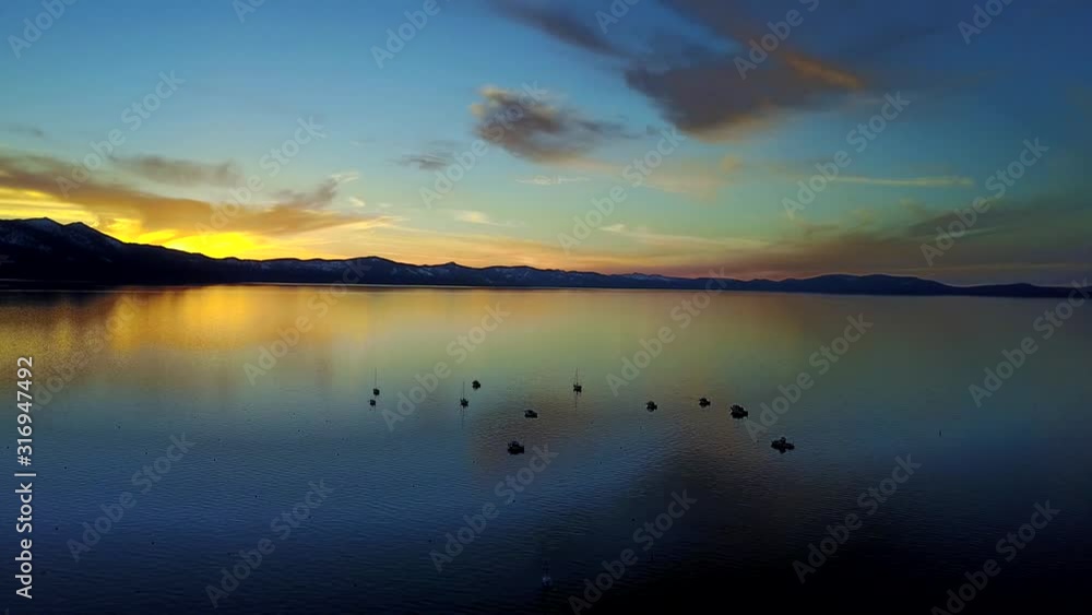 Iconic sunset above Lake Tahoe in United States with boats in foreground, aerial pan shot Iconic sunset above Lake Tahoe in United States with boats in foreground, aerial pan shot
