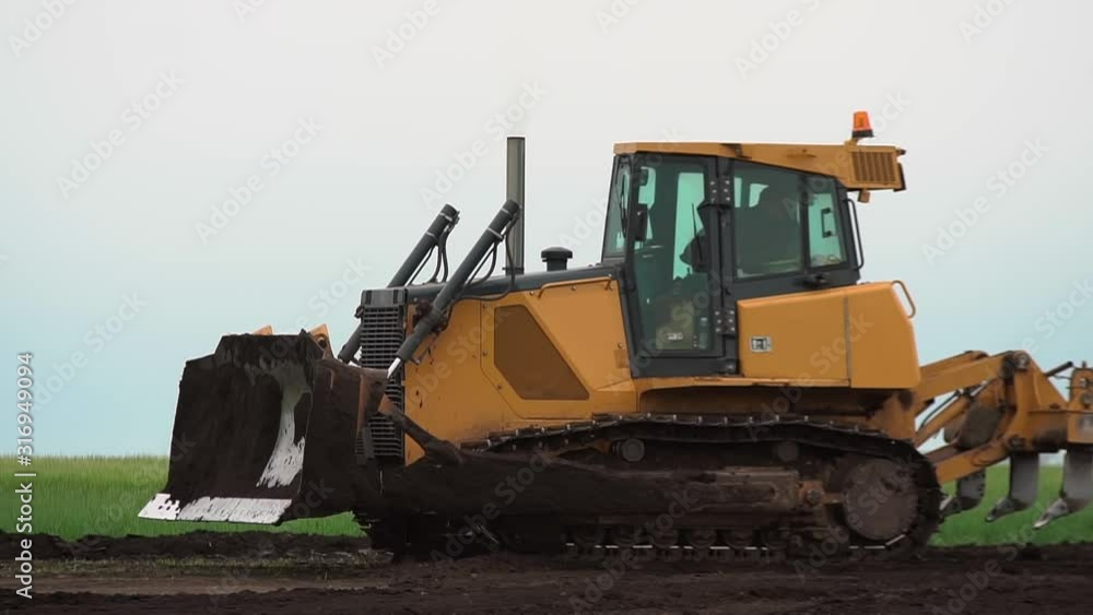 The yellow bulldozer is working. It aligns the black earth The yellow bulldozer is working. It aligns the black earth