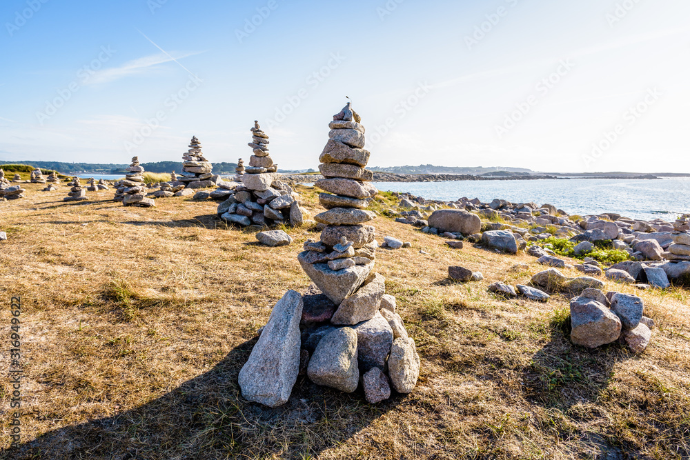 Many man-made granite stone stacks (called cairns) on the coastal path in Brittany, France, on a sunny late afternoon. Many man-made granite stone stacks (called cairns) on the coastal path in Brittany, France, on a sunny late afternoon.