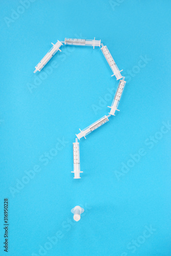 Medical syringes in the form of a question mark. Vertical orientation, top view. © 7707601