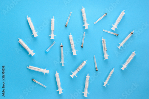 Medical syringes with needles on a blue background. Horizontal orientation, top view, copy space.
