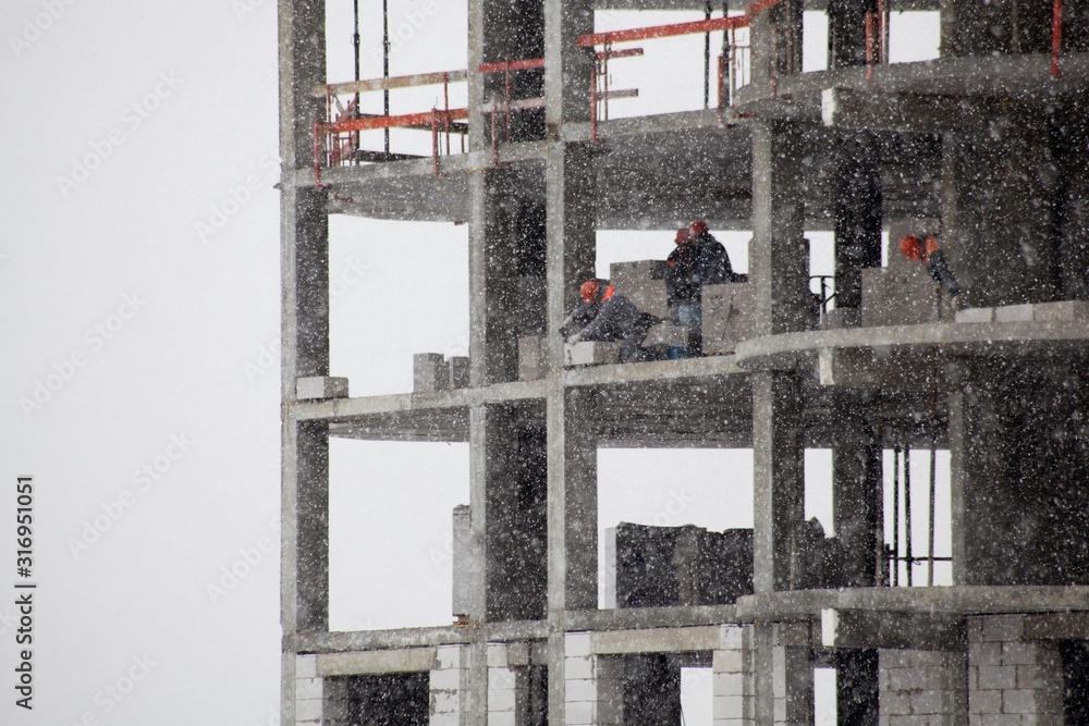 wall of a house under construction with a builder in the window in snowy weather 
