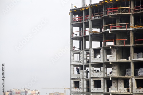 construction of a new house with a builder in the window on a background of gray sky