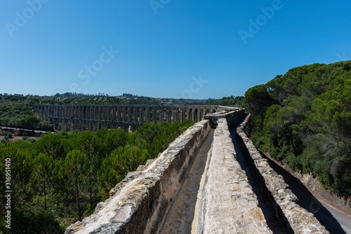 Canvas Print Roman aqueduct of Pegoes surrounded by greenery under sunlight in Tomar in Portu