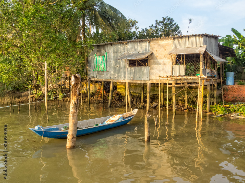 Stilt cabin and a boat in the Mekong River Delta - Can Tho, Vietnam