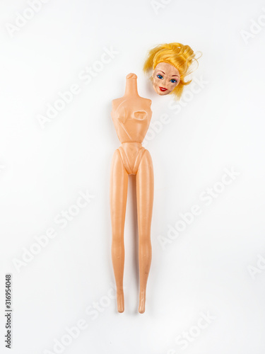 Фотография Broken headless girl doll with torn arm on a white background