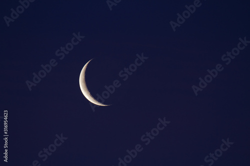 Waning crescent moon in dark blue sky