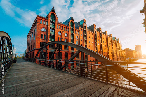 Arch bridge over canals in the Speicherstadt of Hamburg. Warm evening sun light on red brick building photo