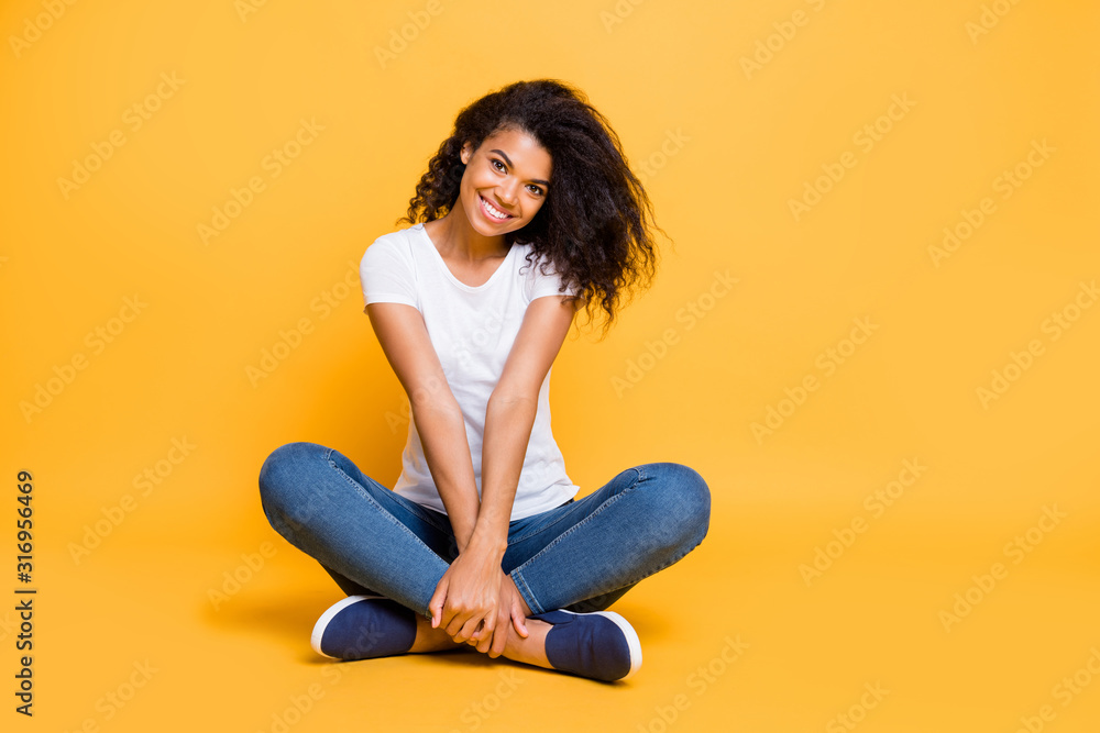 Full length body size photo of cheerful positive cute nice charming pretty girl in jeans denim footwear sitting with legs crossed isolated over vivid color background Full length body size photo of cheerful positive cute nice charming pretty girl in jeans denim footwear sitting with legs crossed isolated over vivid color background