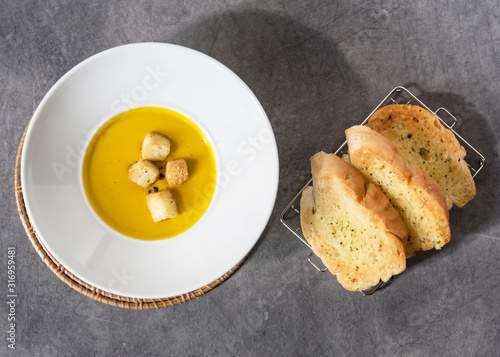 Pumpkin soup with croutons bread in plate garlic bread on stone background with blank space
