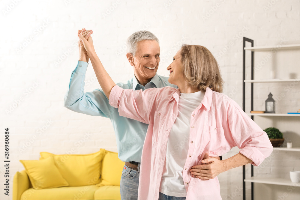 Happy senior couple dancing together in living room Happy senior couple dancing together in living room
