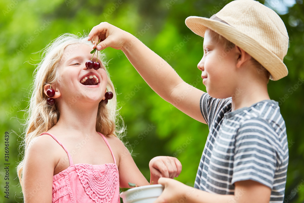 Junge füttert seine Schwester mit Kirschen Stock Photo | Adobe Stock