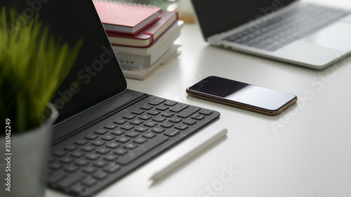 Cropped shot of digital tablet, smartphone, laptop, copy space and other office supplies on white table