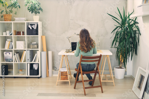 Back view of young attractive female sitting in office.