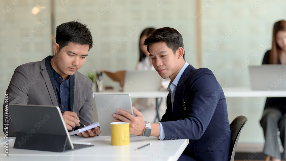 Close up view of two of businessman discussing on their task in modern co working space room Close up view of two of businessman discussing on their task in modern co working space room