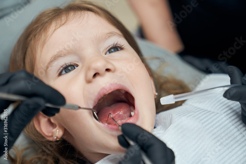Dentist examining condition of teeth of little patient