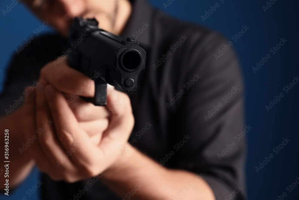 Man holding gun on dark blue background, focus on barrel Man holding gun on dark blue background, focus on barrel