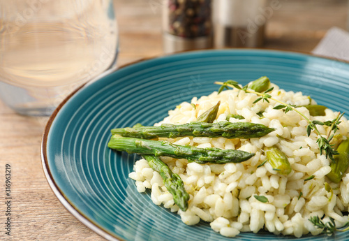 Delicious risotto with asparagus served on wooden table, closeup