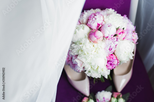 Fototapeta Naklejka Na Ścianę i Meble -  Pair of elegant and stylish bridal shoes with a bouquet with roses and other flowers