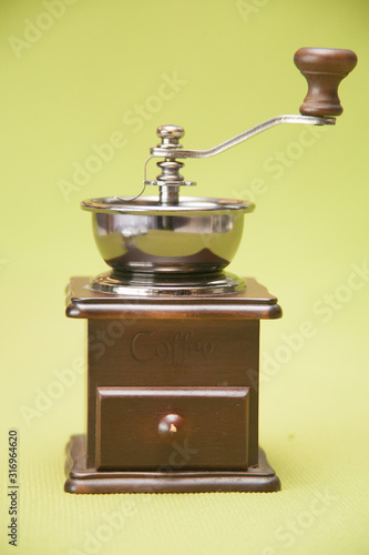 Vintage wooden manual coffee grinder. Close-up isolated on green background