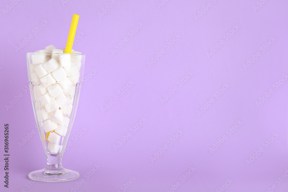 Refined sugar cubes in cocktail glass with straw on lilac background. Space for text Refined sugar cubes in cocktail glass with straw on lilac background. Space for text