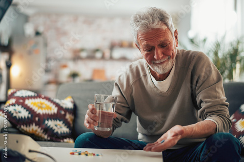 Fotografia Old man taking pills. Senior drinking medicine.