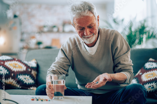 Old man taking pills. Senior drinking medicine. 