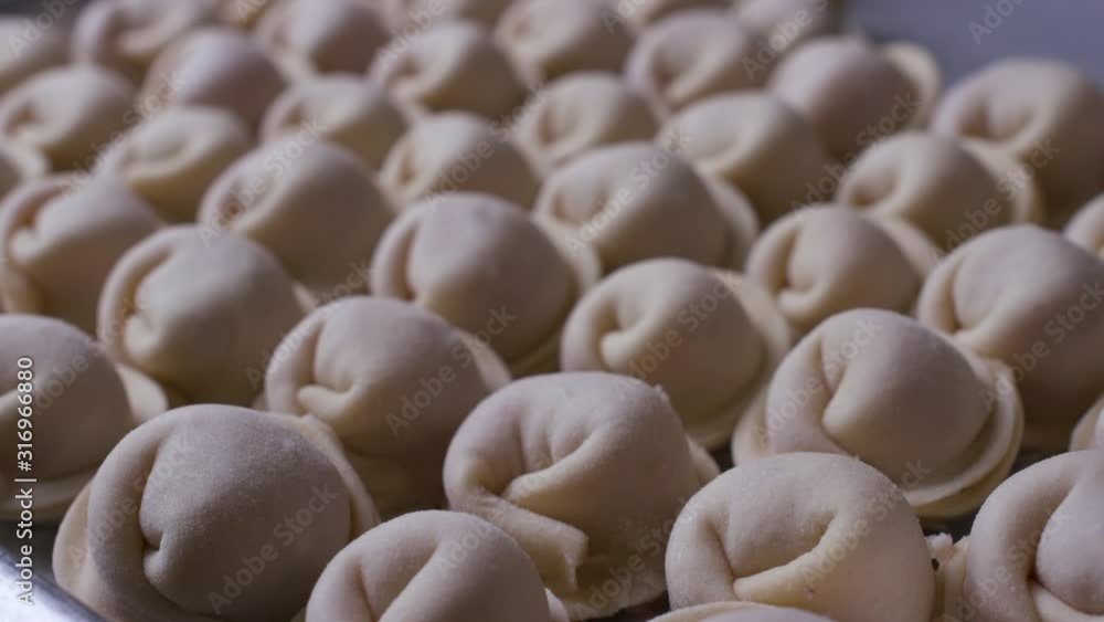 A tray filled with dumplings, waiting for freezing. A tray filled with dumplings, waiting for freezing.