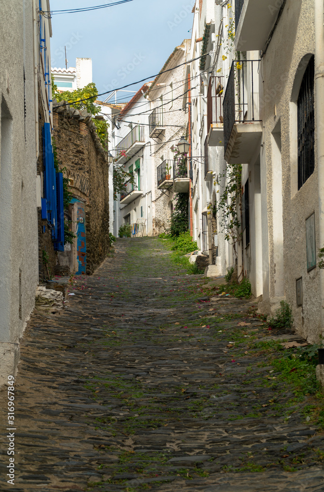 Cadaqués, Catalonia / Spain - November 30th, 2019: Old narrow cobbled street in the old village center