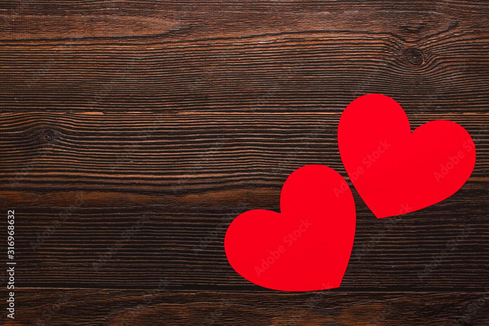 Two paper hearts isolated on a dark wooden background. Top side view of a celebrating warm flatlay. Valentines day and Christmas concept. Copyspace. Two paper hearts isolated on a dark wooden background. Top side view of a celebrating warm flatlay. Valentines day and Christmas concept. Copyspace.