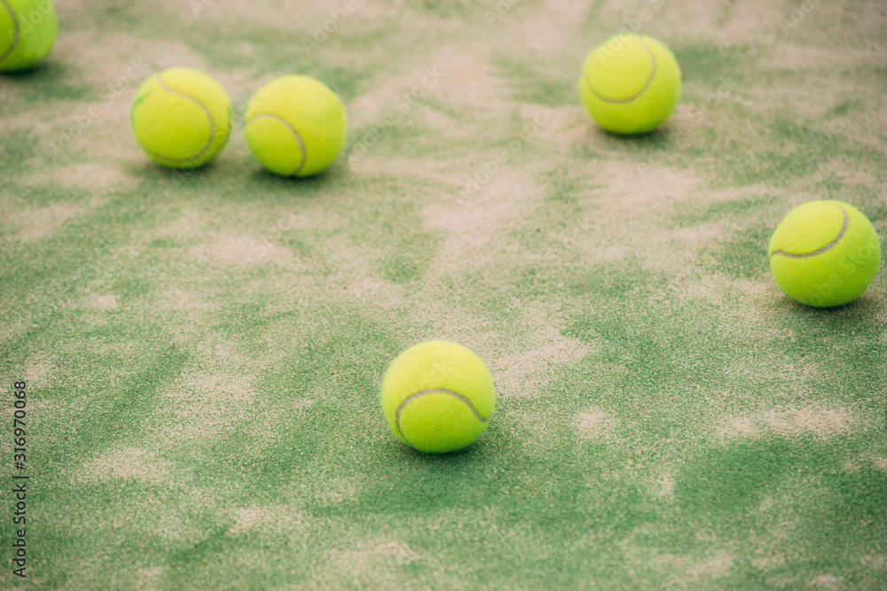 Paddle balls on the floor of a green outdoor paddle court