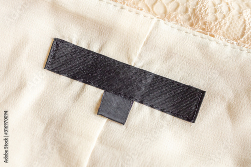 Blank black laundry care clothing label on fabric texture