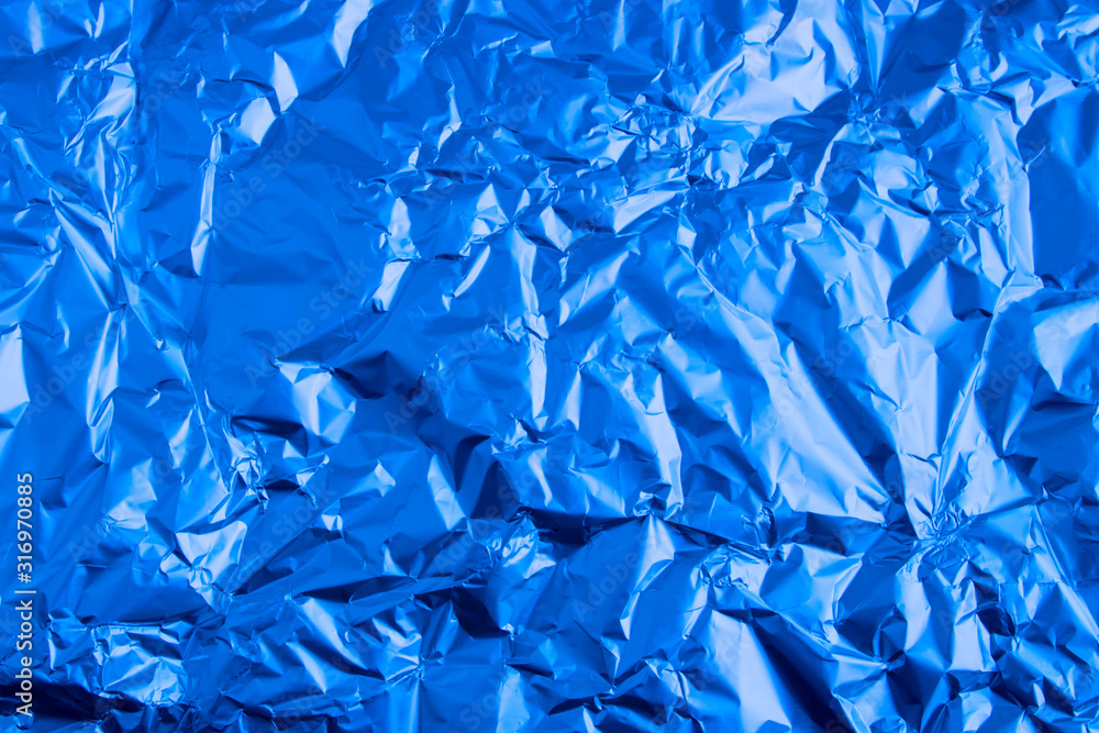 Obraz premium Abstract trendy blue colored crumpled foil texture background. 2020 year color trend concept.